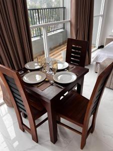 a wooden table with two chairs and a table with wine glasses at Ruish City Kandy in Kandy