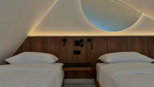 two beds in a room with a round mirror at The Orbital in Fanari +40 photos