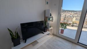 a living room with a flat screen tv and a window at City Flights in Kavála