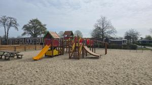 a playground with a slide and a bench in the sand at Het Strandnest in Renesse