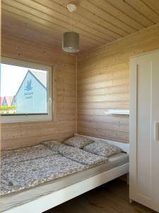 a bed in a wooden room with a window at Szara Gąska w Gąskach in Gąski