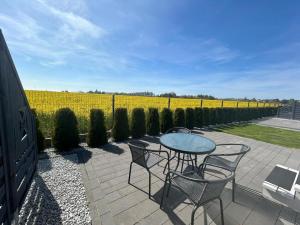 a patio with a table and chairs and a row of bushes at Szara Gąska w Gąskach in Gąski