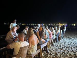 a group of people sitting in chairs on the beach at Surf Wave Hotel in Arugam Bay
