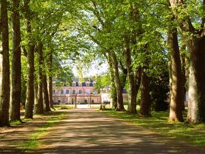 a tree lined road with a house in the background at Domaine du Chesne in Salbris