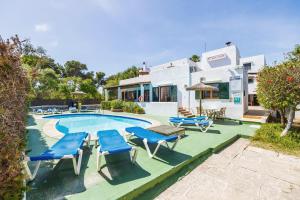 a swimming pool with blue chairs and a house at Apartamento Felipe 2-2 in Cala d´Or