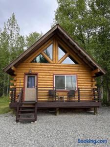 a log cabin with two chairs and a door at Hatcher Pass Cabins in Palmer