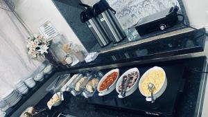 a kitchen counter with plates of food on a stove at Hotel Colonial in Pôrto Ferreira +10 photos
