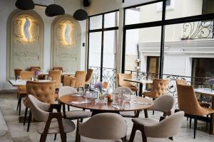 a restaurant with tables and chairs and windows at Hotel Goya Collection in Târgu Jiu