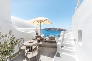 a patio with a table and chairs and an umbrella at Just Blue in Oia