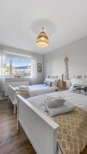 a white bedroom with two beds and a large window at No 1 Rhosffordd in Moelfre