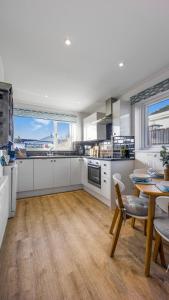a kitchen with white cabinets and a table and a dining room at No 1 Rhosffordd in Moelfre +60 photos