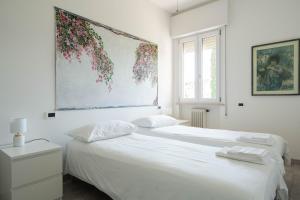 two beds in a white bedroom with a painting on the wall at Villa Livia in Toscolano Maderno