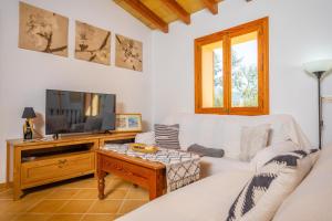 a living room with a white couch and a tv at Es Coll d'en Pastor in Fornalutx