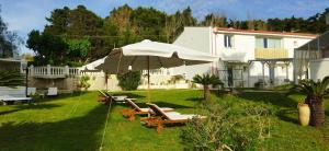 a yard with chairs and an umbrella and a house at Dimora Idruntina in Otranto
