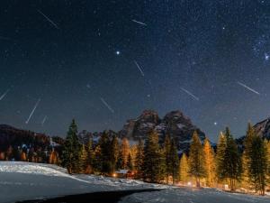 a starry night with trees and a mountain at Camping Cadore in Selva di Cadore