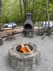a stone fire pit in a park with a picnic table at WildBeauty Grebaje in Vusanje