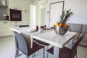 a kitchen with a table with a bowl of fruit on it at Aurea Attico con Jacuzzi e vista mare Lignano in Lignano Sabbiadoro +10 photos