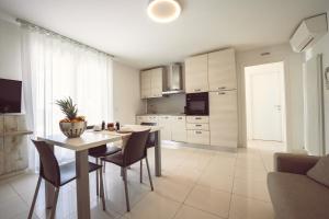 a kitchen with a table and chairs in a room at Aurea Attico con Jacuzzi e vista mare Lignano in Lignano Sabbiadoro