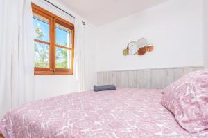 a bedroom with a bed with a pink comforter and a window at Son Bou in Sóller +29 photos