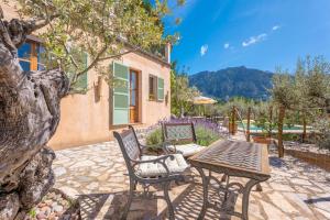 a patio with a table and chairs and a house at Son Bou in Sóller