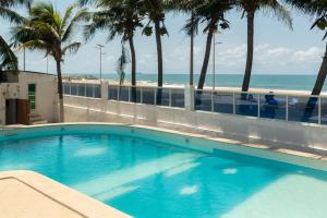 a swimming pool with palm trees and the beach at Guesthouse Chez Marco in Cotonou