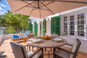 a patio with a table and chairs and an umbrella at Cala Dor 14 in Cala d´Or