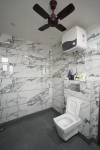 a bathroom with a white toilet and a ceiling fan at FlexiBay Boys Hostel Noida in Noida