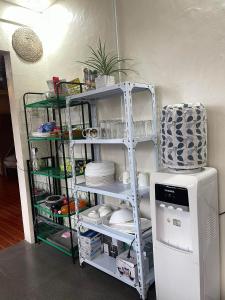 a shelf with plates and dishes on it next to a refrigerator at Pine's View Casa Isabel Villa Staycation - Marilog, Davao City in Kayagan