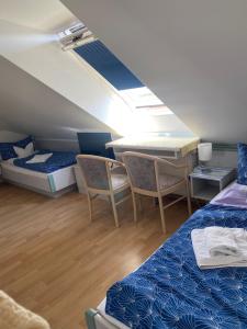 a room with two beds and a table and chairs at Hotel Sylvia in Norderney