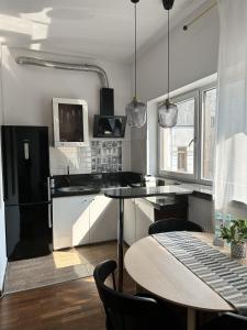 a kitchen with a table and a black refrigerator at Villa Masoneria in Łódź