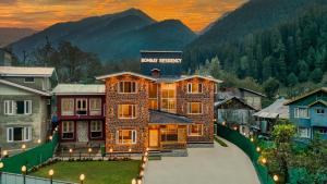a large building with a sunset in the mountains at Bombay Residency in Pahalgām