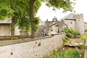 two people riding bikes on a stone wall in front of a castle at Im Prummehuck in Raeren