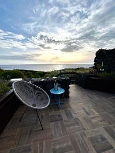 a patio with a chair and a table and the ocean at Dammuso Bacio Pantesco in Pantelleria +11 photos