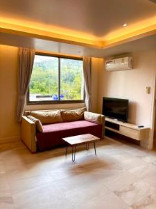 a living room with a couch and a large window at Adventure Condo Aonang in Ao Nang Beach