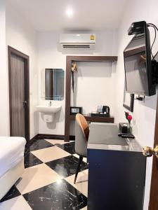 a room with a bed and a desk with a television at The CHESS Samui in Chaweng
