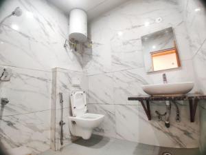 a white bathroom with a sink and a toilet at Hans Cottage in Shimla