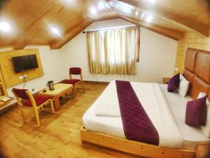 a bedroom with a bed and a table and a tv at Hans Cottage in Shimla