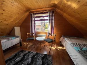 a attic room with two beds and a table and chairs at Domek Twórczy Kąt in Święta Katarzyna