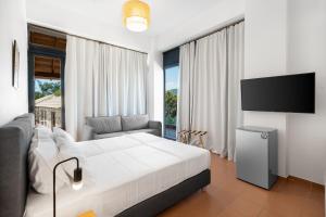 a bedroom with a white bed and a tv at Almyra Holiday Village in Edipsos