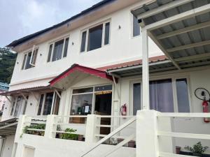 a white house with a porch and a balcony at Hans Cottage in Shimla +8 photos