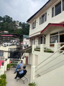 two people sitting on a balcony of a house at Hans Cottage in Shimla