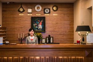 a woman is standing behind a counter in at Jazz Hotel in Danang