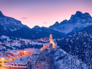 a small town in the mountains at sunset with a church at Camping Cadore in Selva di Cadore