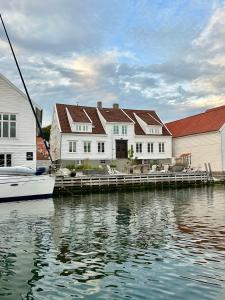 Ein Boot liegt an einem Steg neben Häusern. in der Unterkunft Gamlekaien in Skudeneshavn