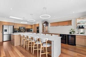 a kitchen with a large white island with bar stools at Werri Big Beach House in Gerringong
