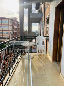 a balcony with two white chairs and a table at HD Luxury Apparts in Yaoundé