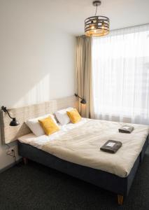 a bedroom with a large bed with yellow pillows at KVARC Hotel in Valmiermuiža +90 photos