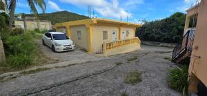 a white car parked in front of a yellow building at Cozy Hub -B in Philipsburg