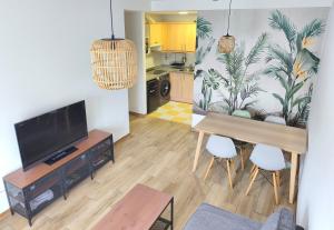 a living room with a television and a table and chairs at Apartamentos DEVA in Unquera