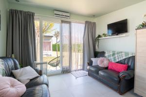 a living room with a leather couch and a television at Wonderful chalet in De Haan in De Haan